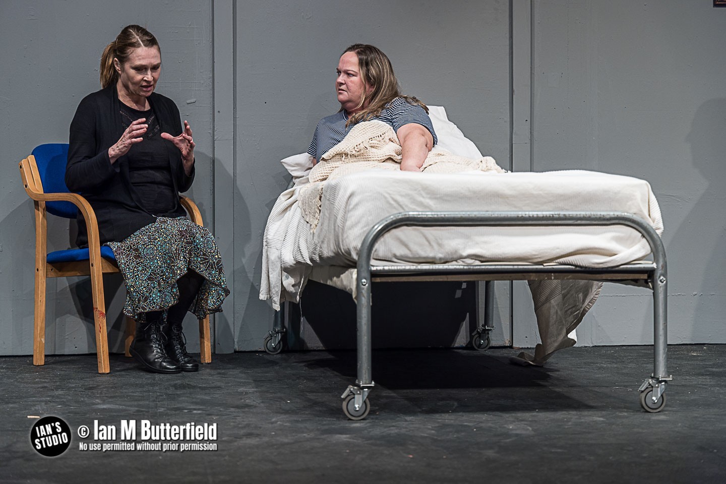 A women in bed with another women sat next to her