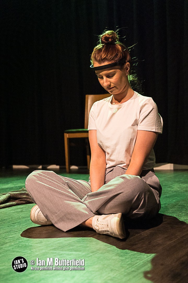 A woman sat on the floor with a black tech headset on her forehead