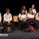 Lots of teenagers in school unforms sat on chairs