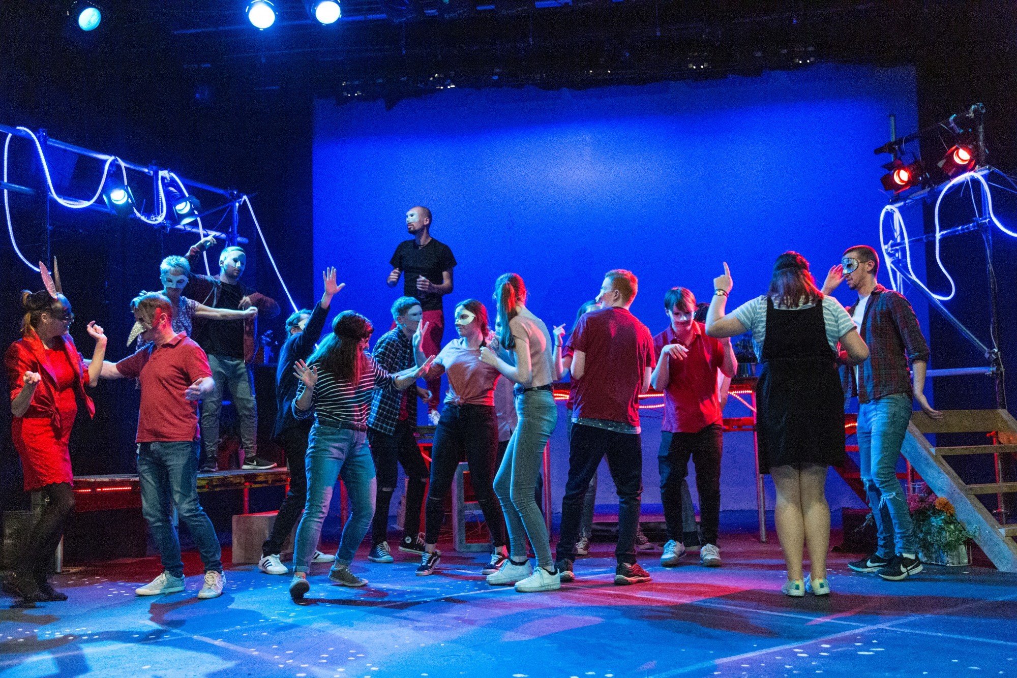 A group of people on stage dacning whilst all wearing masks